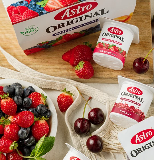 Astro Fruit on the bottom yogurt small tubs and the multi-pack packing on a table with various fruit on a table